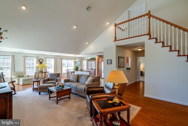 living area with plenty of natural light, stairs, visible vents, and wood finished floors