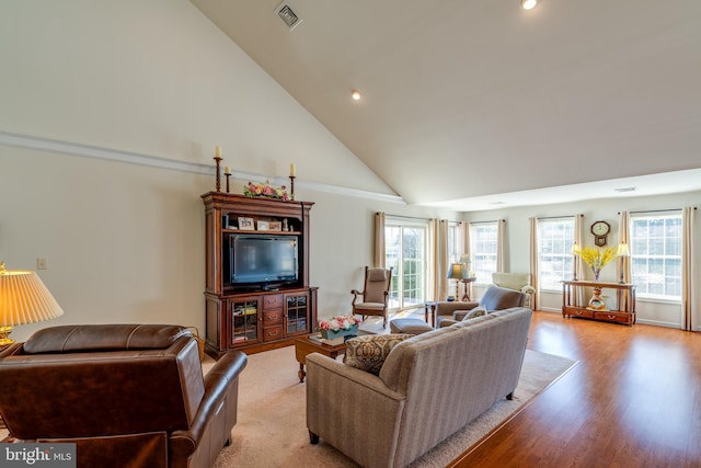 living area featuring high vaulted ceiling, light wood-type flooring, visible vents, and recessed lighting