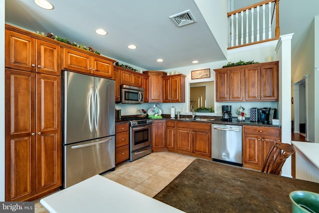 kitchen with stainless steel appliances, brown cabinetry, visible vents, and a sink