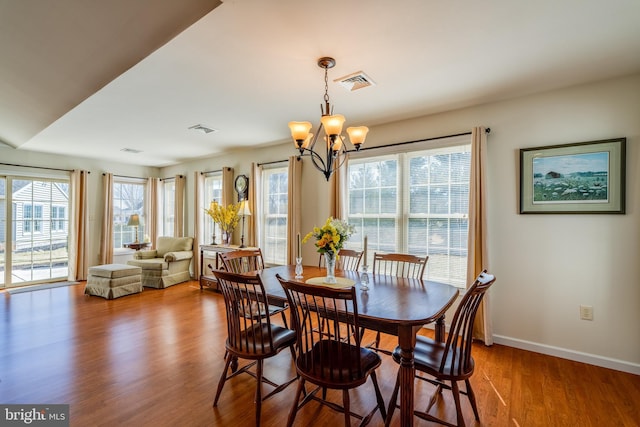 dining room featuring an inviting chandelier, visible vents, baseboards, and wood finished floors