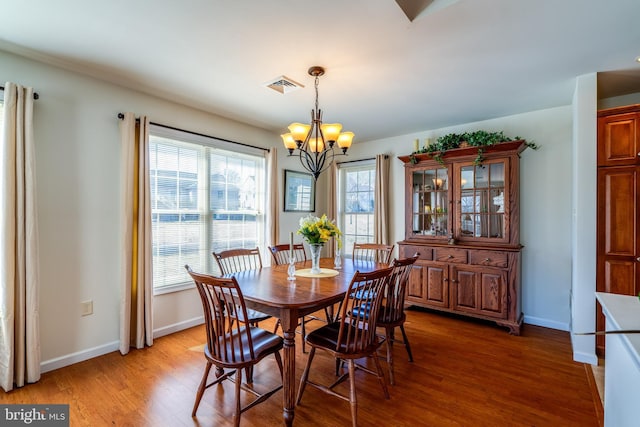 dining space with light wood finished floors, baseboards, visible vents, and a chandelier