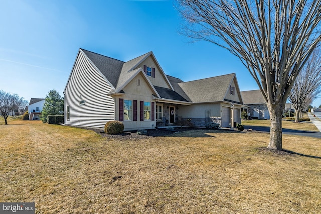 view of front facade featuring a front yard, stone siding, and an attached garage