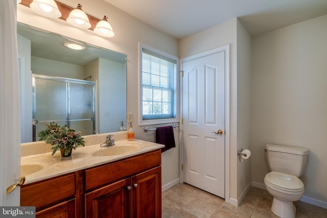 bathroom with double vanity, toilet, a sink, a shower stall, and tile patterned floors