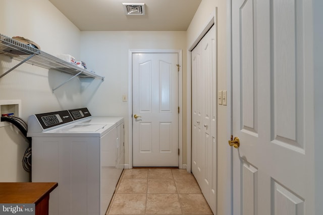 washroom with washing machine and dryer, laundry area, light tile patterned flooring, and visible vents