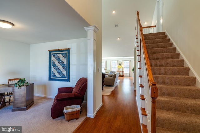 foyer entrance featuring a high ceiling, visible vents, baseboards, stairway, and decorative columns