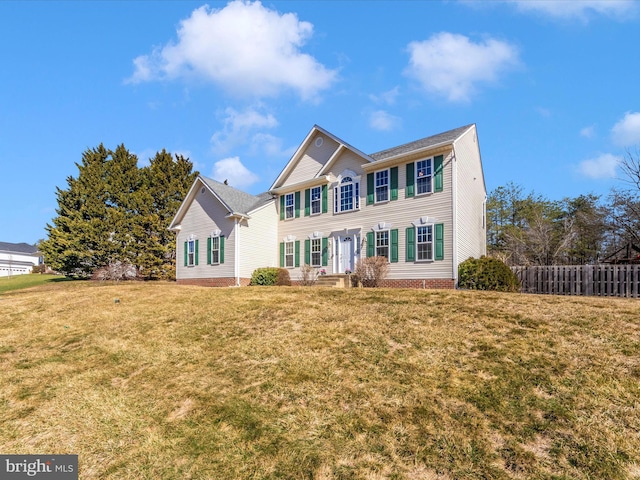 colonial inspired home featuring a front yard and fence