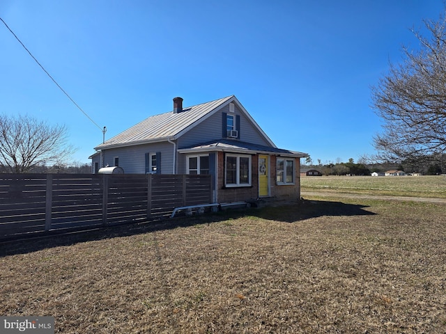 view of front of home featuring a chimney, a front yard, a standing seam roof, metal roof, and fence