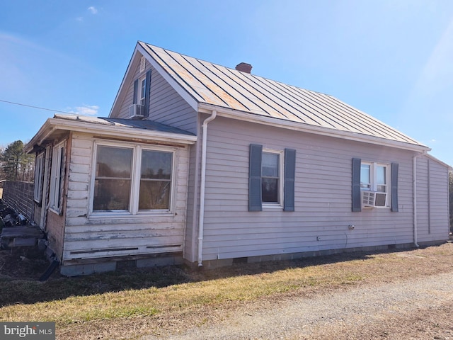 view of side of property with metal roof, crawl space, a standing seam roof, and a chimney