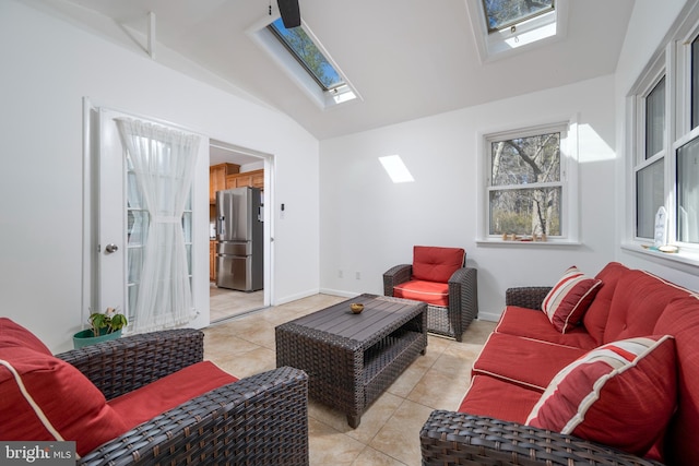 living room featuring vaulted ceiling with skylight, light tile patterned floors, and baseboards