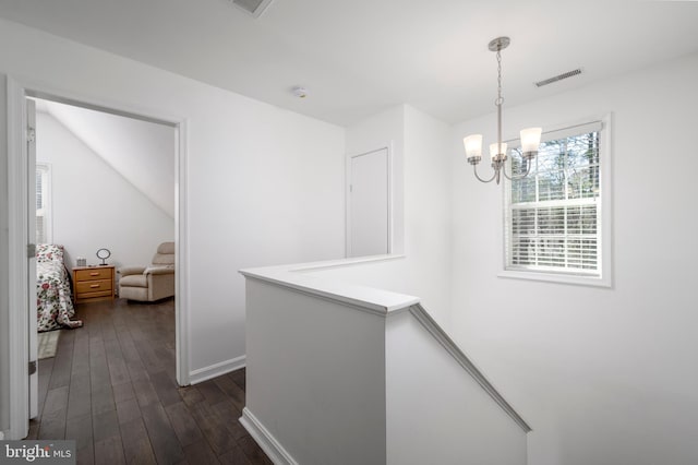 hall with visible vents, baseboards, dark wood finished floors, an upstairs landing, and a notable chandelier