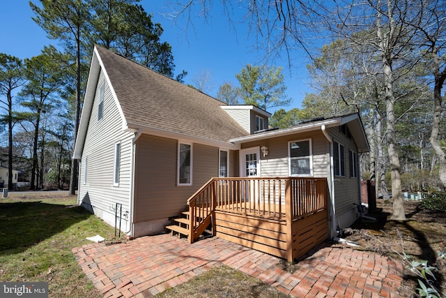 view of front of home with a front yard, a patio area, roof with shingles, and a wooden deck