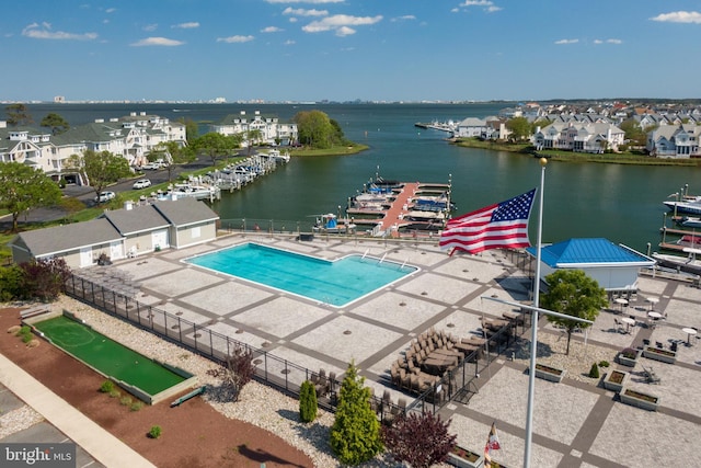 view of pool featuring fence, a water view, and a residential view