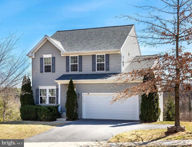 view of front facade with driveway, an attached garage, and a shingled roof