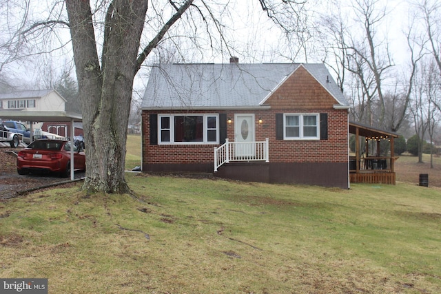 view of front of home featuring a front lawn, brick siding, and roof with shingles