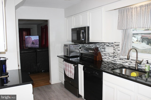 kitchen with a sink, black appliances, white cabinetry, dark countertops, and tasteful backsplash