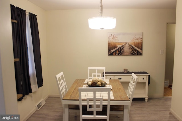 dining space featuring visible vents, baseboards, and wood finished floors