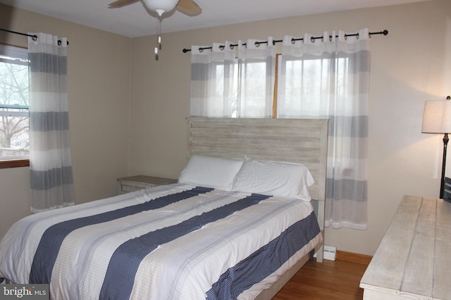 bedroom with ceiling fan, baseboards, and wood finished floors