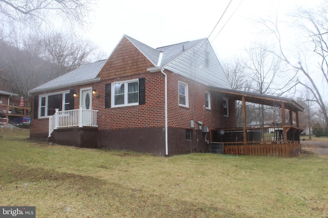 exterior space featuring brick siding, a shingled roof, and a yard