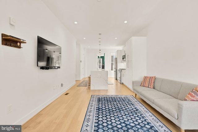 living area with recessed lighting, baseboards, and light wood-style floors