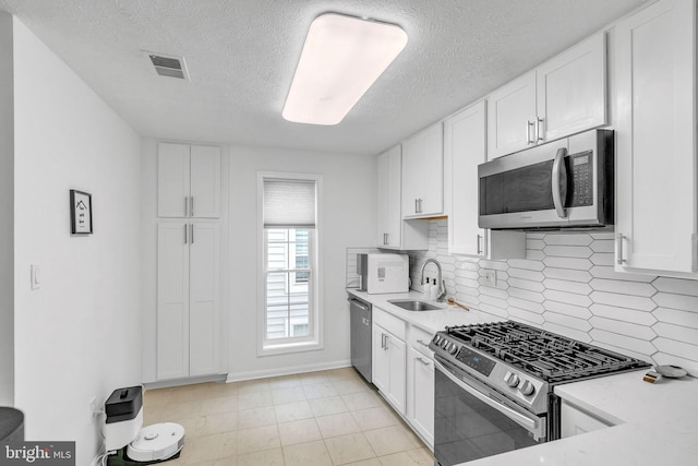 kitchen with visible vents, appliances with stainless steel finishes, light countertops, white cabinetry, and a sink