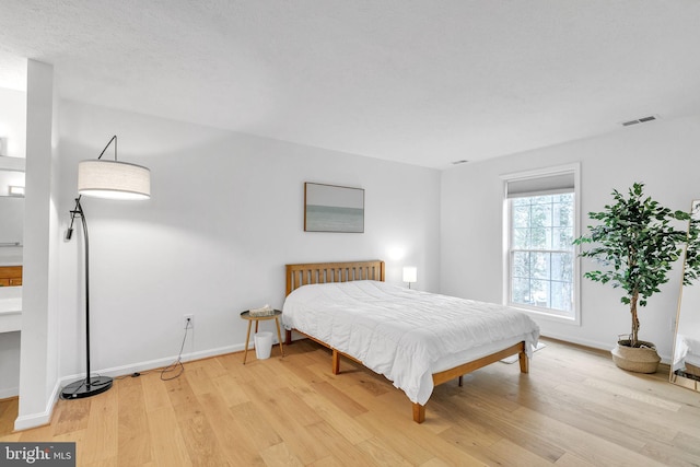 bedroom featuring light wood finished floors, baseboards, and visible vents