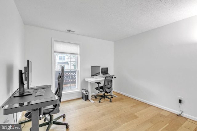 office featuring baseboards, a textured ceiling, visible vents, and wood finished floors