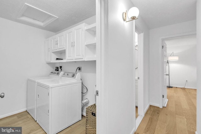 clothes washing area with separate washer and dryer, light wood-style flooring, cabinet space, and attic access