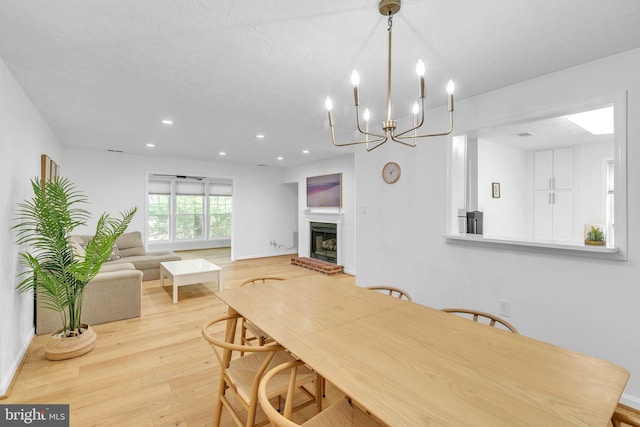 dining room featuring baseboards, wood finished floors, a textured ceiling, a fireplace, and recessed lighting