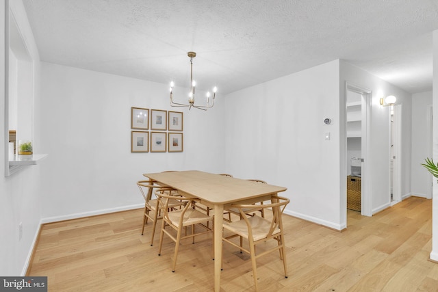 dining space with light wood-style flooring, baseboards, and a textured ceiling