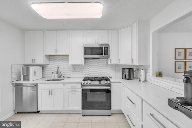 kitchen with stainless steel appliances, a sink, light countertops, and white cabinetry