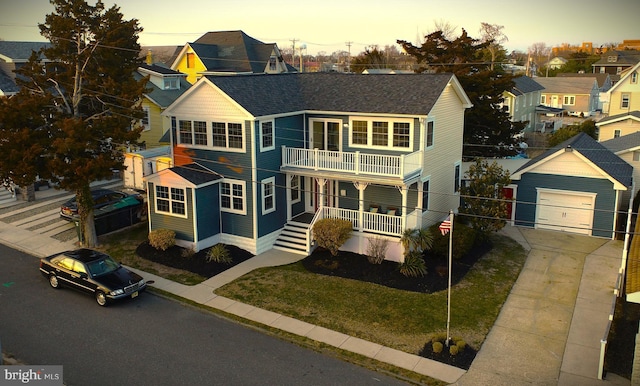 view of front of house with a balcony, driveway, a porch, an outdoor structure, and a garage