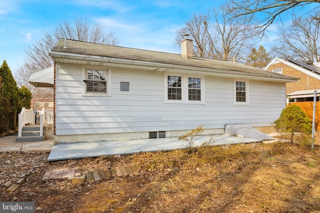 back of house with a chimney and fence