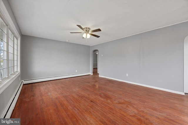 unfurnished room featuring a baseboard heating unit, a ceiling fan, arched walkways, and hardwood / wood-style flooring