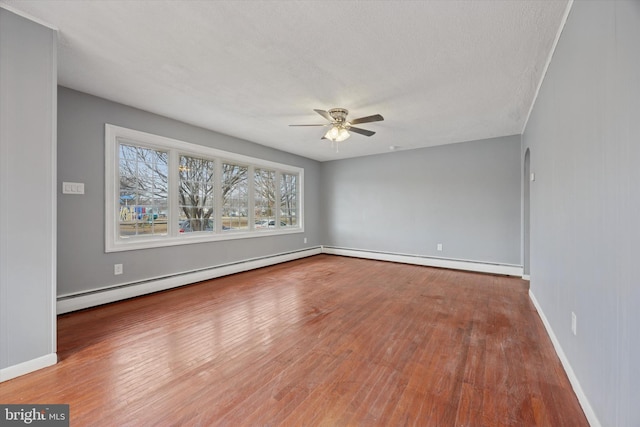 empty room featuring a baseboard radiator, ceiling fan, and wood finished floors