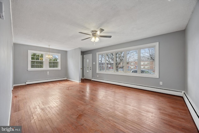 unfurnished living room with a baseboard heating unit, ceiling fan with notable chandelier, baseboard heating, and hardwood / wood-style flooring