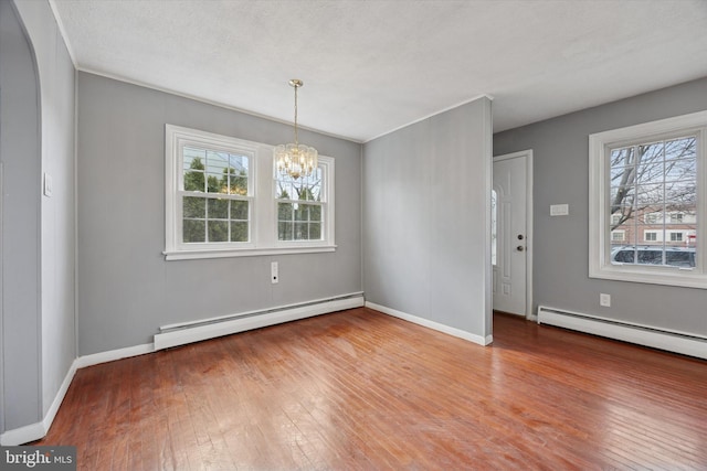 unfurnished dining area featuring an inviting chandelier, a baseboard radiator, wood-type flooring, and a wealth of natural light