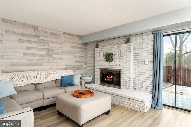 living room with wood walls, a brick fireplace, and wood finished floors