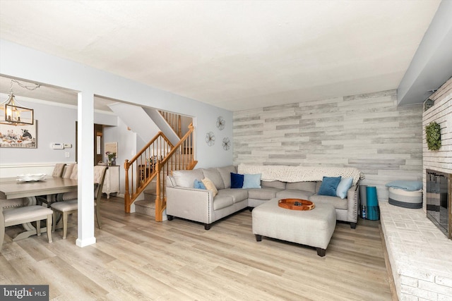 living area with light wood finished floors, a brick fireplace, and stairs