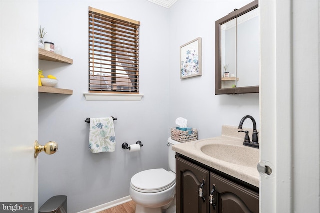 half bath featuring toilet, vanity, baseboards, and wood finished floors