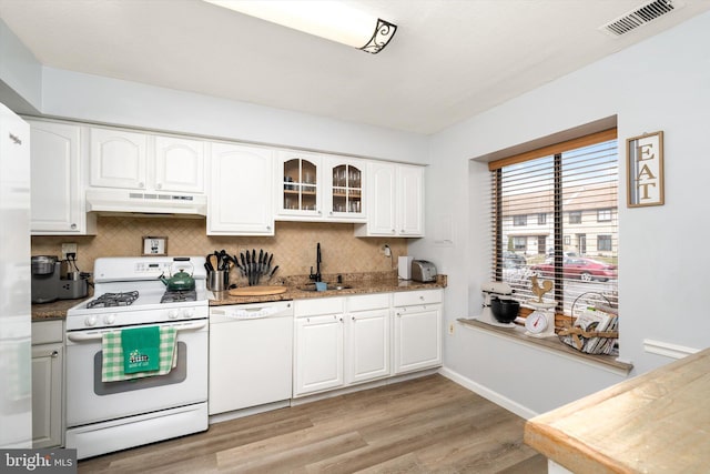 kitchen featuring white appliances, visible vents, a sink, under cabinet range hood, and tasteful backsplash