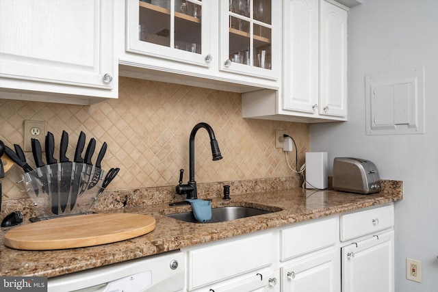 kitchen featuring white cabinets, glass insert cabinets, backsplash, and a sink
