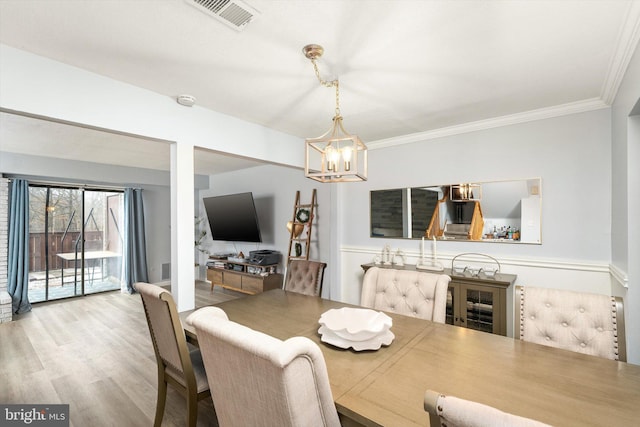 dining area with ornamental molding, wood finished floors, visible vents, and a chandelier