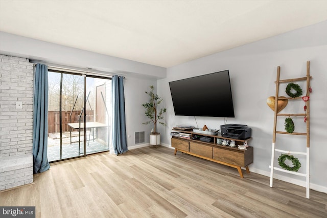 living area with visible vents, baseboards, and wood finished floors