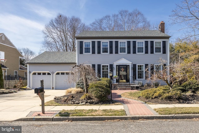 view of front of house with roof with shingles, a chimney, concrete driveway, fence, and a garage