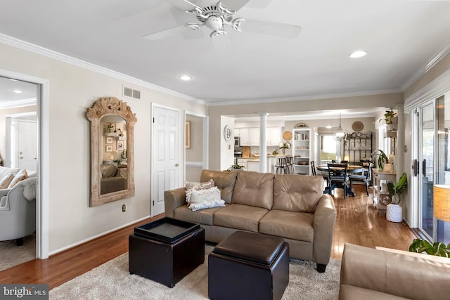 living room with ornamental molding, wood finished floors, visible vents, and ornate columns