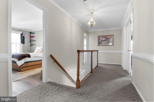 hall with a chandelier, carpet, an upstairs landing, and crown molding