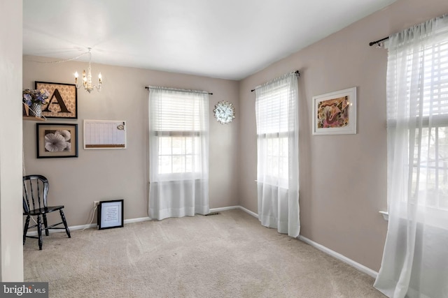 carpeted empty room with baseboards and a chandelier