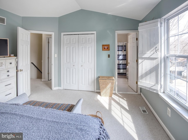 carpeted bedroom featuring lofted ceiling, a closet, multiple windows, and visible vents