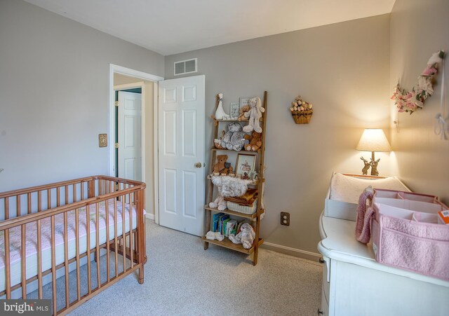 carpeted bedroom featuring a crib, visible vents, and baseboards