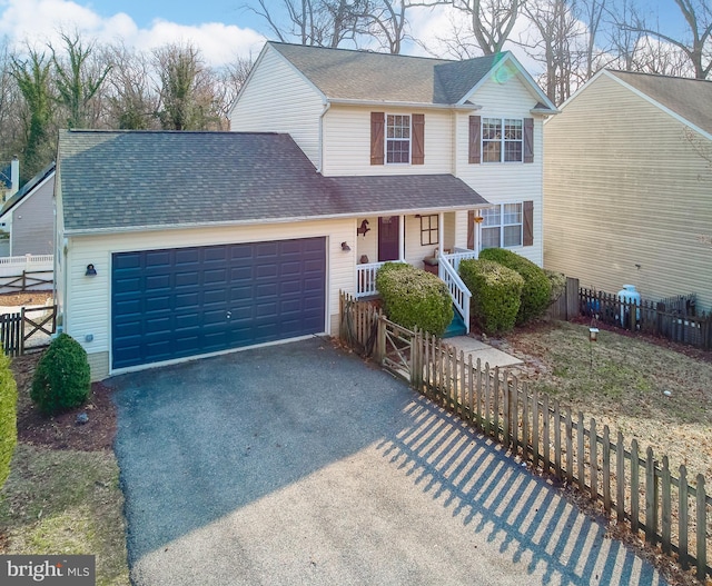 traditional-style home featuring driveway, a fenced front yard, a porch, and a shingled roof